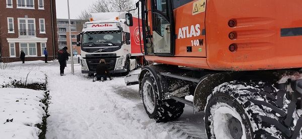 Loonwerker en bergers druk bezig met vast gereden vrachtwagens (video)