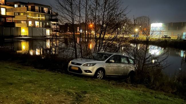 Auto rolt van oprit het water in