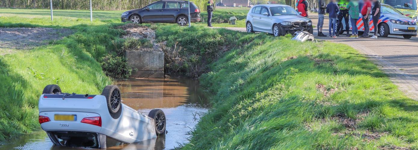 Auto op de kop in de sloot na botsing op kruising