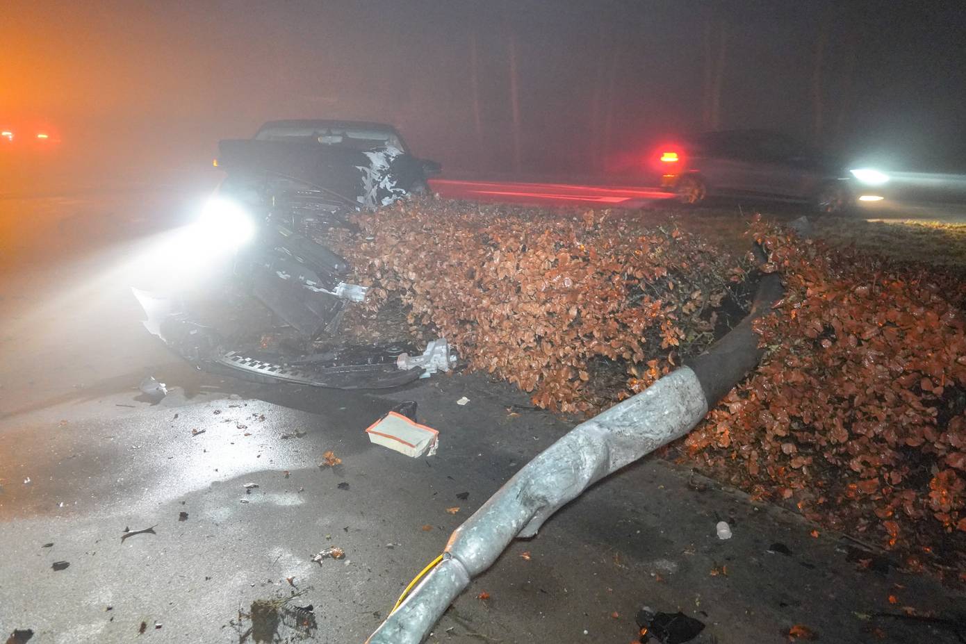 Auto mist bocht en botst tegen betonblok en lantaarnpaal en belandt in bosjes (Video)