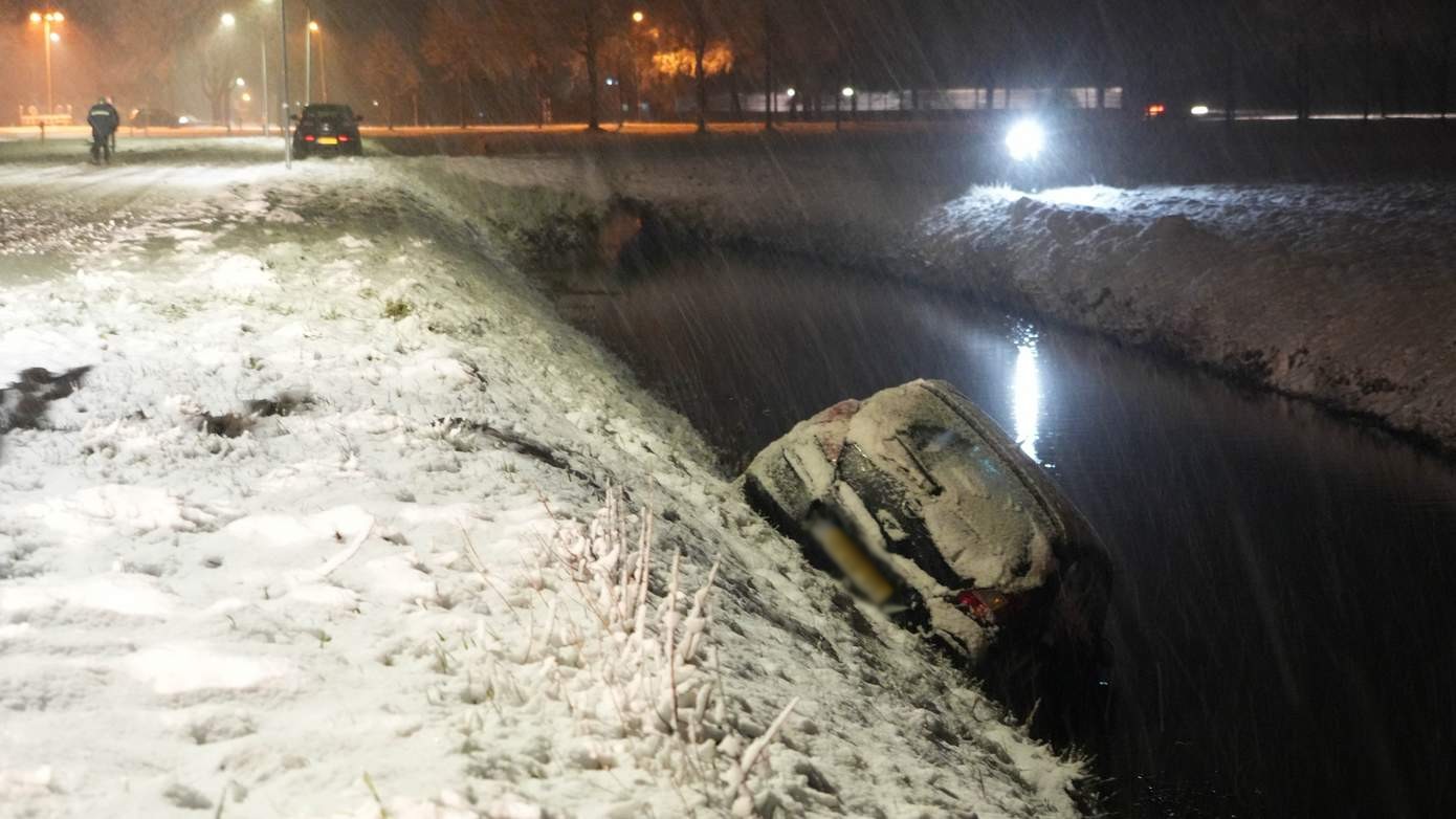 Auto schiet rechtdoor op besneeuwde kruising en hangt boven sloot