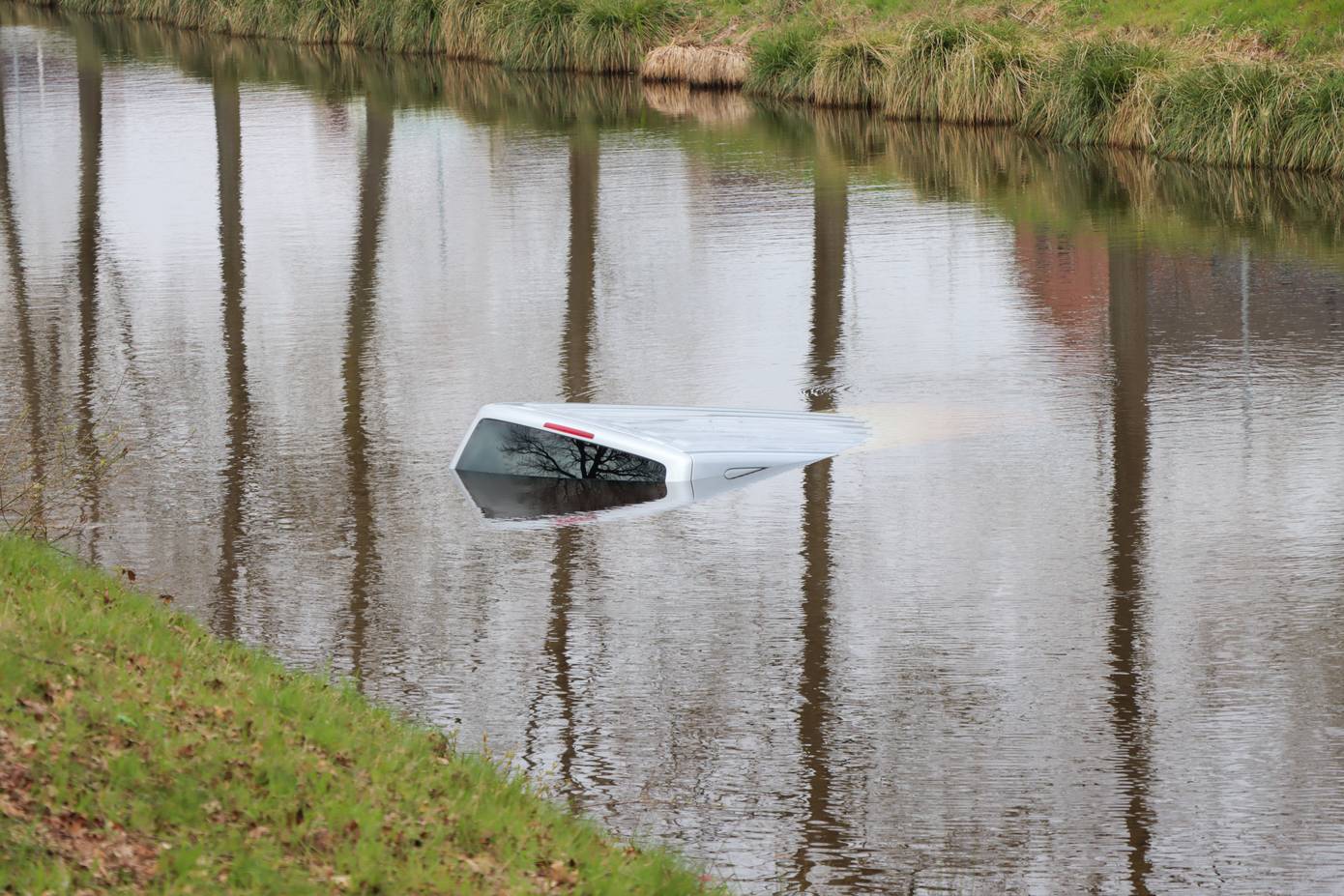 Busje rolt in Zwartemeer van oprit het water in